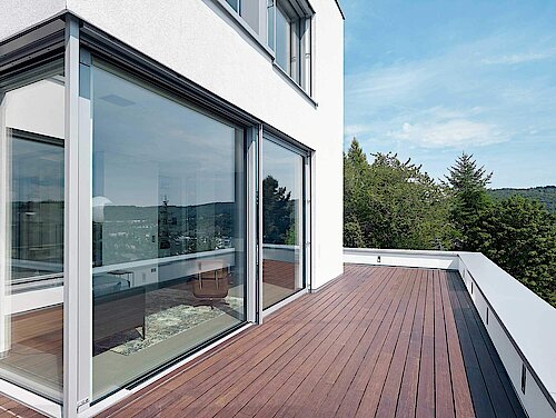 Blick von einer Terrasse auf ein modernes weißes Haus mit Schüco Alu-Fenster 