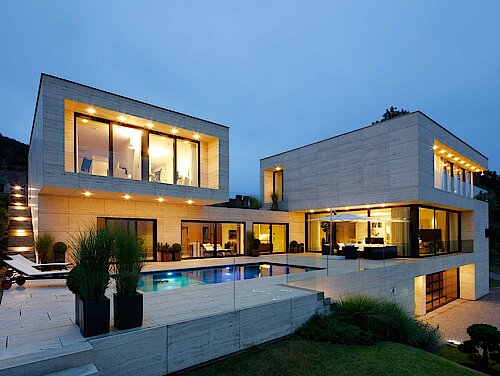 Blick auf eine große moderne Villa mit selbstlüftenden Schüco Alu-Fenster am Abend